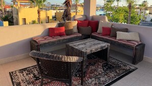 A balcony with a sofa set, a wicker chair, and a coffee table.