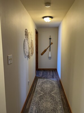 En hall med en mönstrad matta, en väggmonterad paddel och en taklampa.