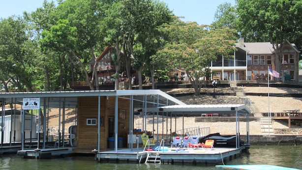 A dock with a covered seating area, a boat, and a building in the background. - 2 Master Suites, Incredible Views Sleeps 10-12, Great Dock (Sunrise Beach)