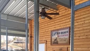 A covered outdoor seating area with metal beams and a wooden wall. A sign reads "Captain Bruno's". - 2 Master Suites, Incredible Views Sleeps 10-12, Great Dock (Sunrise Beach)