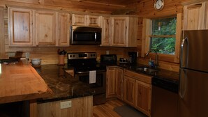 Une cuisine rustique aménagée dans une cabane en bois, avec des appareils intégrés, notamment une cuisinière, un four à micro-ondes et un réfrigérateur.