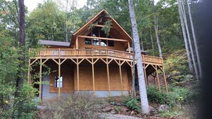 Une cabane en bois dotée d’un balcon, entourée d’arbres.
