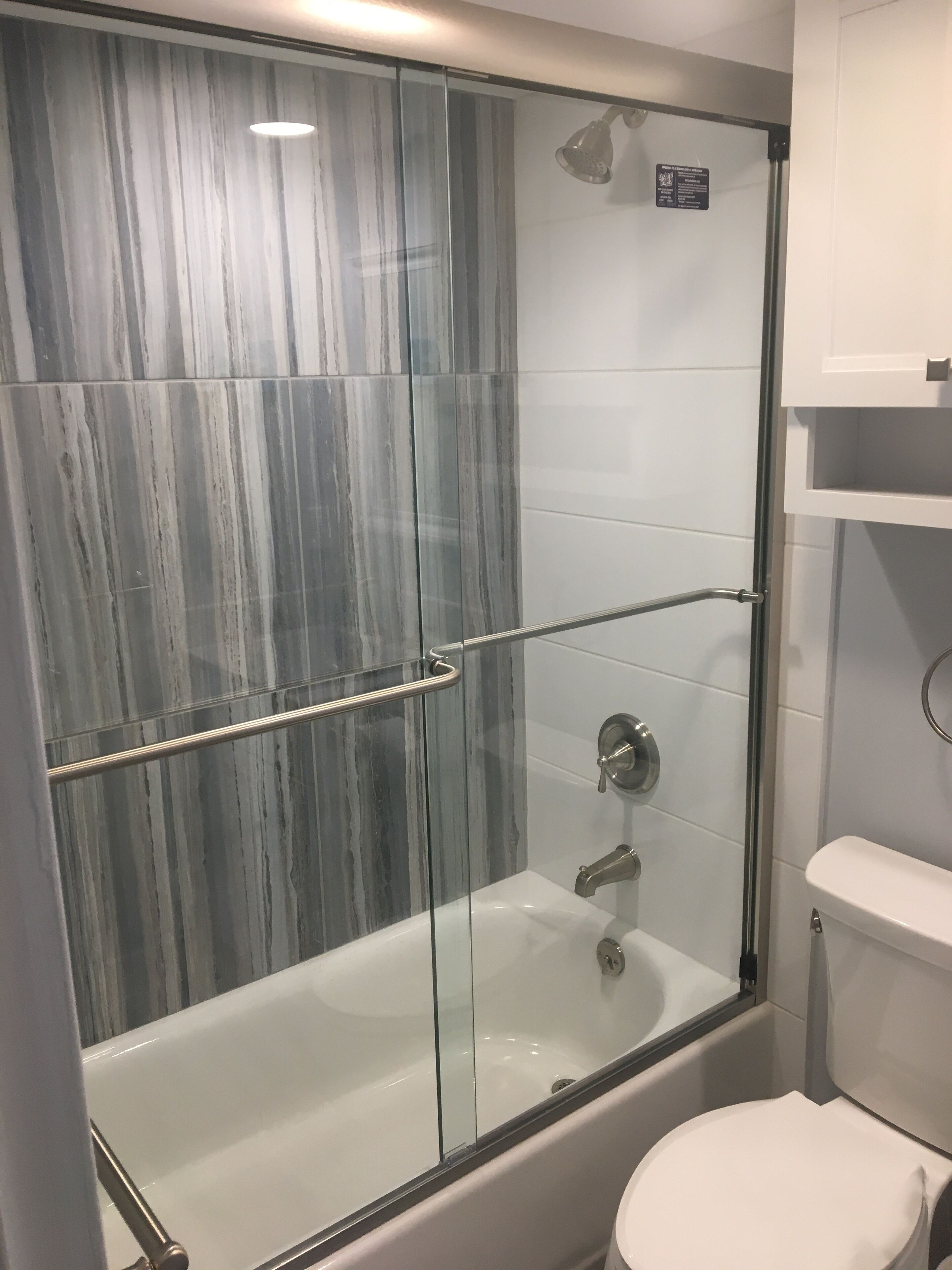 A modern bathroom with a glass-enclosed shower, a white toilet, and a built-in sink.