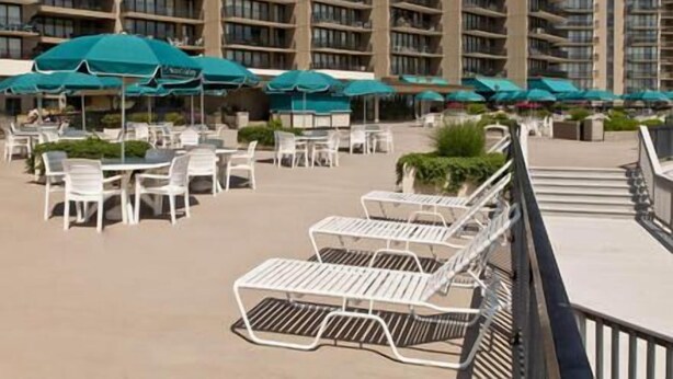 Un hotel con zonas de estar al aire libre, varios niveles de balcones y un cielo despejado.