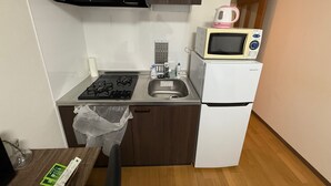 Eine kleine Küche mit einem Gasherd, einer Mikrowelle und einem Kühlschrank.