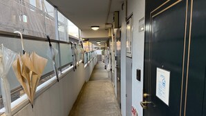 Ein Hotelkorridor mit einem Feuerlöscher, einer Tür mit einem Schild und Regenschirmen, die an der Wand hängen.