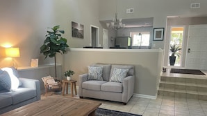 A living room with a wooden coffee table, a grey sofa with patterned cushions, a potted plant, and a small round table with a lamp. - WOW! WHAT A DEAL for a HOUSE in SeaPines! Great Locations 2 BR -Pets ok (Hilton Head Island)