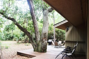 A wooden deck with a grill and chairs, surrounded by trees. - WOW! WHAT A DEAL for a HOUSE in SeaPines! Great Locations 2 BR -Pets ok (Hilton Head Island)