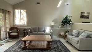 A living room with a sofa, a coffee table, a chair, and a large plant. - WOW! WHAT A DEAL for a HOUSE in SeaPines! Great Locations 2 BR -Pets ok (Hilton Head Island)