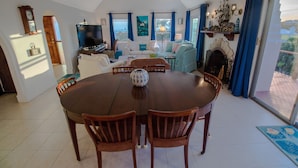 A spacious living room with a round wooden dining table surrounded by chairs, a television, and a fireplace. - [A]MOUR HEART OF HOSPITALITY! (Hamilton)