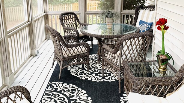 A covered porch with wicker furniture, a glass table, and a black and white patterned rug. - Lovely Home, Perfect location, Coliseum, Golf, HPU, Back Porch & Community pool (Jamestown)