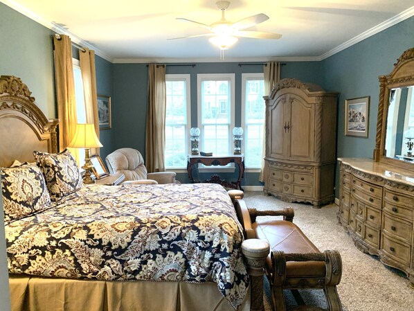 A bedroom with a large bed, a dresser, a chair, and a desk.