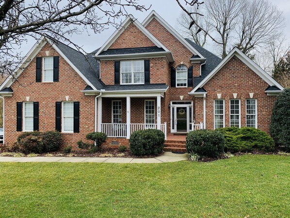 A two-story brick house with a front porch, a garage door, and a well-maintained lawn. - Lovely Home, Perfect location, Coliseum, Golf, HPU, Back Porch & Community pool (Jamestown)