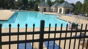 A swimming pool with a fenced area, lounge chairs, and a small building with a green roof. - Lovely Home, Perfect location, Coliseum, Golf, HPU, Back Porch & Community pool (Jamestown)