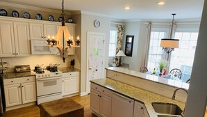 A kitchen with white cabinets, a wooden bench, a stove, a dishwasher, and a window with curtains. - Lovely Home, Perfect location, Coliseum, Golf, HPU, Back Porch & Community pool (Jamestown)