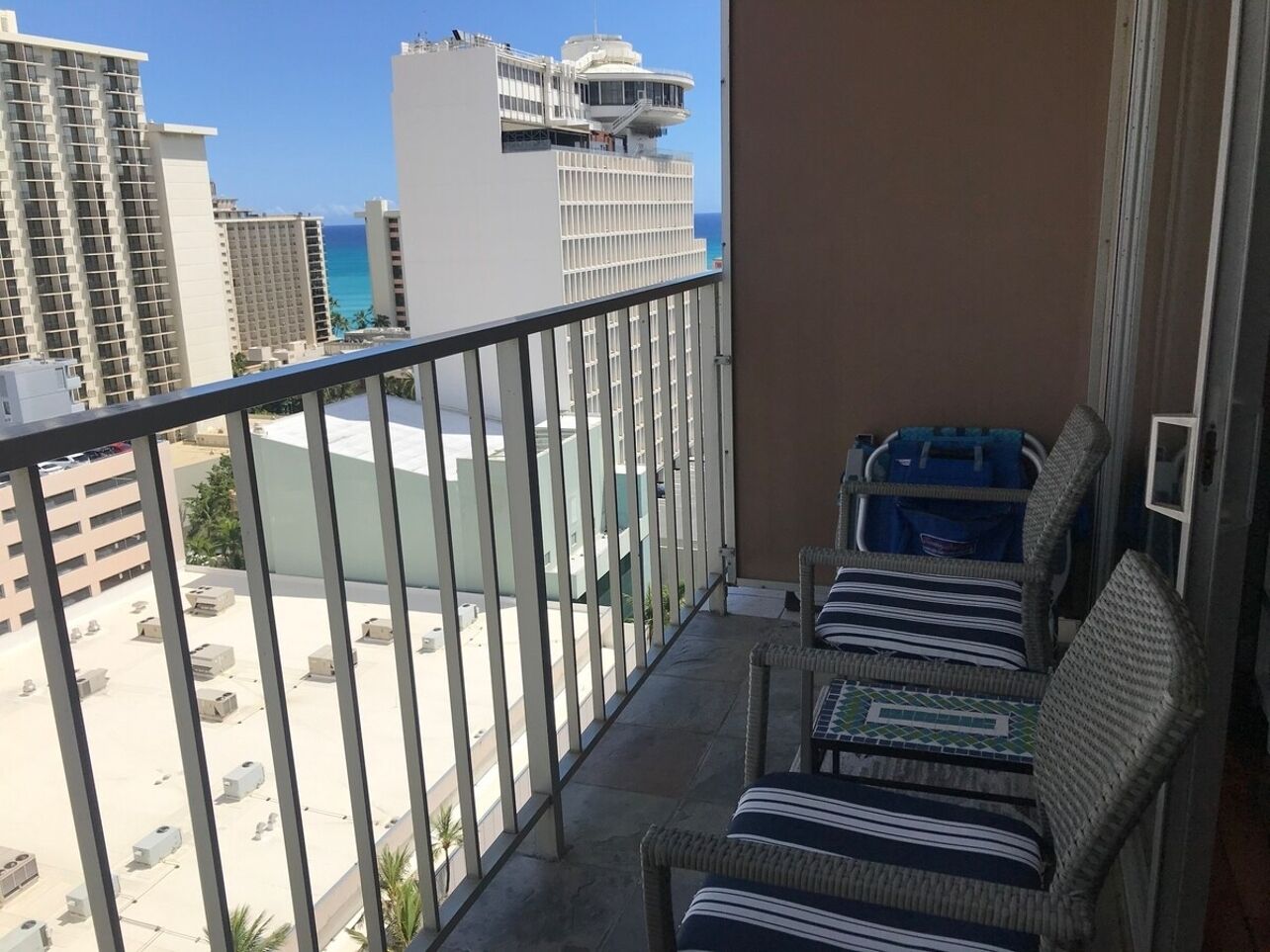 Ein Balkon mit Korbstühlen und Blick auf das Meer und die Bebauung.