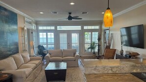 A spacious living room with a beige sofa, a coffee table, and a TV mounted on the wall. - Gulf Front With Great Views And Pool! (Ocean Springs)