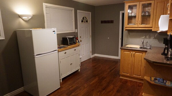 A compact kitchen with a refrigerator, microwave, and wooden cabinets. - New Zealand Hospitality In The Okanagan (Peachland)