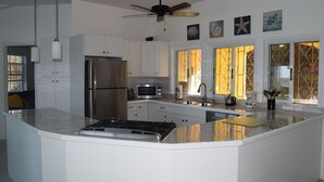 A modern kitchen with white cabinetry, stainless steel appliances, and a central island. - Beautiful views, walk to Secret Harbour Beach (St. Thomas, VI)