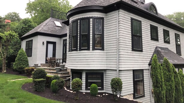 A two-story house with a curved corner design, a balcony, and a chimney.