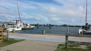 A marina with boats docked, a wooden walkway, and houses in the background. - Great Beach House - Kill Devil Hills, One Row from Oceanfront (Kill Devil Hills)