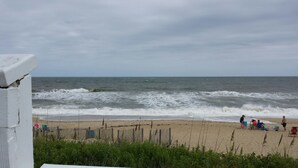 A beach with a wooden fence, people relaxing, and the ocean in the background. - Great Beach House - Kill Devil Hills, One Row from Oceanfront (Kill Devil Hills)