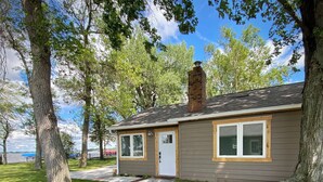A house with a front yard, a pathway leading to the door, and trees surrounding the property. - Relaxing Lakefront Cabin, Family + Lake + Dock + Sunset + Be Here, All Year Fun! (Watertown)
