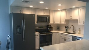 A modern kitchen with white cabinets, stainless steel appliances, and a marble countertop.