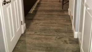 A hallway with a dark wood floor, a white door on the left, and a white door on the right.