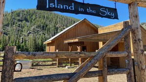 Een houten hutje met een bord waarop staat 'Island in the Sky' en een bergachtige achtergrond.