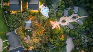 An aerial view of a residential area with multiple houses, a swimming pool, and a well-maintained lawn. - The Gathering House: Fun outdoor nature vibes w pool 15 minutes to Waco, TX. (Crawford)