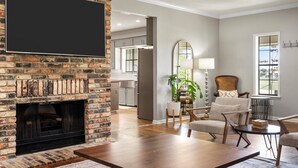 A living room with a fireplace, a television, and a dining area. - The Gathering House: Fun outdoor nature vibes w pool 15 minutes to Waco, TX. (Crawford)