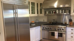 Una cocina moderna con electrodomésticos de acero inoxidable, suelo de madera y armarios blancos.