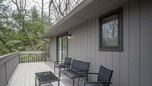 En overdækket terrasse med bord og stole, gelænder og et vindue.
