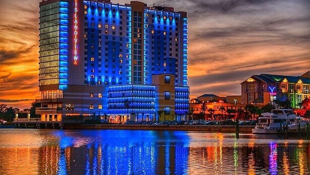 A high-rise hotel with a modern design, featuring multiple balconies and a prominent 'Island' sign. - Agape Bay - Sienna on the Coast Unit 102 (Gulfport)