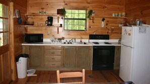 A wooden cabin kitchen with a stove, microwave, sink, and cabinets. - Private, Secluded, Relaxing Cabin.   1853
Ask about out WEDDING OPPORTUNITIES (Blairsville)
