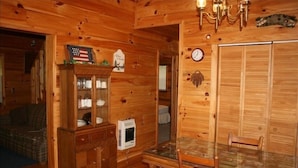 A wooden cabin interior with a dining table, chairs, a clock, a fireplace, and a television. - Private, Secluded, Relaxing Cabin.   1853
Ask about out WEDDING OPPORTUNITIES (Blairsville)