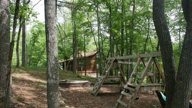 A rustic cabin surrounded by tall trees, a wooden swing set, and a wooden ladder. - Private, Secluded, Relaxing Cabin.   1853
Ask about out WEDDING OPPORTUNITIES (Blairsville)
