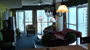 Ein Hotelzimmer mit einer Couch, Sesseln, einem Couchtisch, einem Fernseher und einem Kronleuchter.