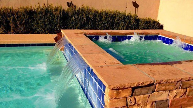 A swimming pool with a waterfall feature and a separate hot tub area. - Albuquerque Home w/ Heated Pool & Hot Tub Near Balloon Fiesta (Albuquerque)