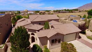 A residential area with multiple houses featuring terracotta roofs and beige walls, surrounded by greenery and a mountainous backdrop. - Albuquerque Home w/ Heated Pool & Hot Tub Near Balloon Fiesta (Albuquerque)