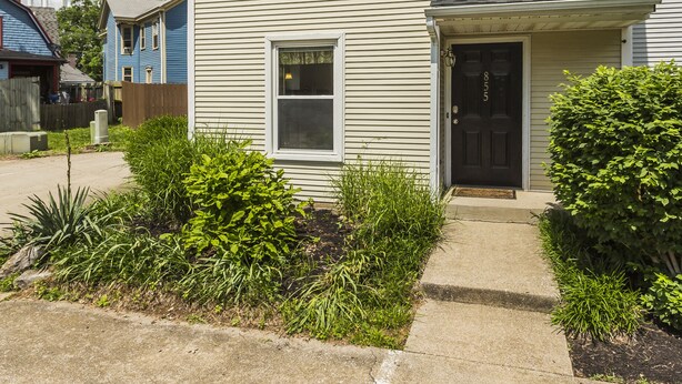A two-story building with a front entrance, a small porch, and a visible water tower in the background. - Downtown Townhouse Near Rupp Arena (Lexington)