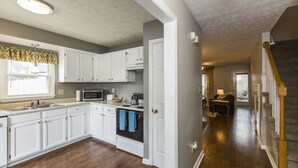 A kitchen with white cabinets, a microwave, and a stove. - Downtown Townhouse Near Rupp Arena (Lexington)