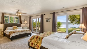 Une chambre avec deux lits, un ventilateur de plafond et une vue sur un lac.