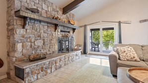 Une cheminée en pierre avec une cheminée décorative, un canapé et un coin repas avec une table et des chaises.