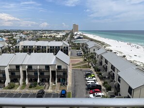 A resort with multiple-story buildings, a parking lot, and a beach with a pier in the background.