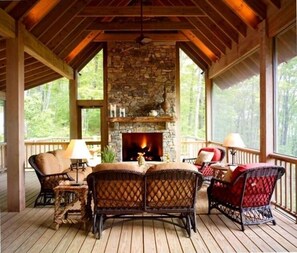 A covered porch with wicker furniture, a stone fireplace, and a view of the forest. - Upscale Cottage with Ultra Privacy and Spectacular View (Sapphire)