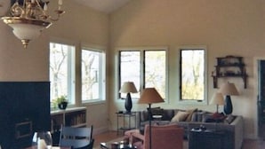 A spacious living room with a high ceiling, a dining area with a wooden table and chairs, a sofa set, and a fireplace. - Mountainview House - Luxurious Privacy Above the Clouds (Aquone)