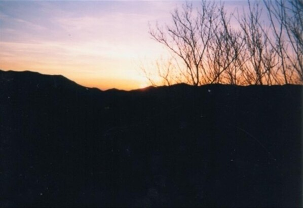 A silhouette of a mountain range against a sunset sky.