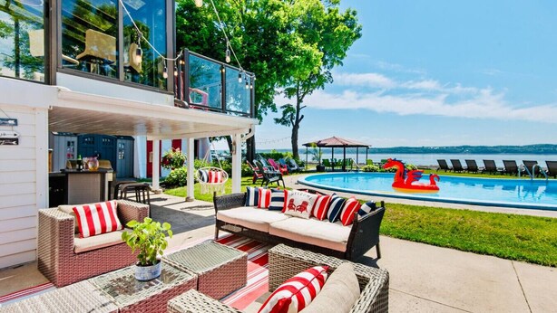 Un espacio exterior moderno con piscina, mobiliario de mimbre y vistas al mar.